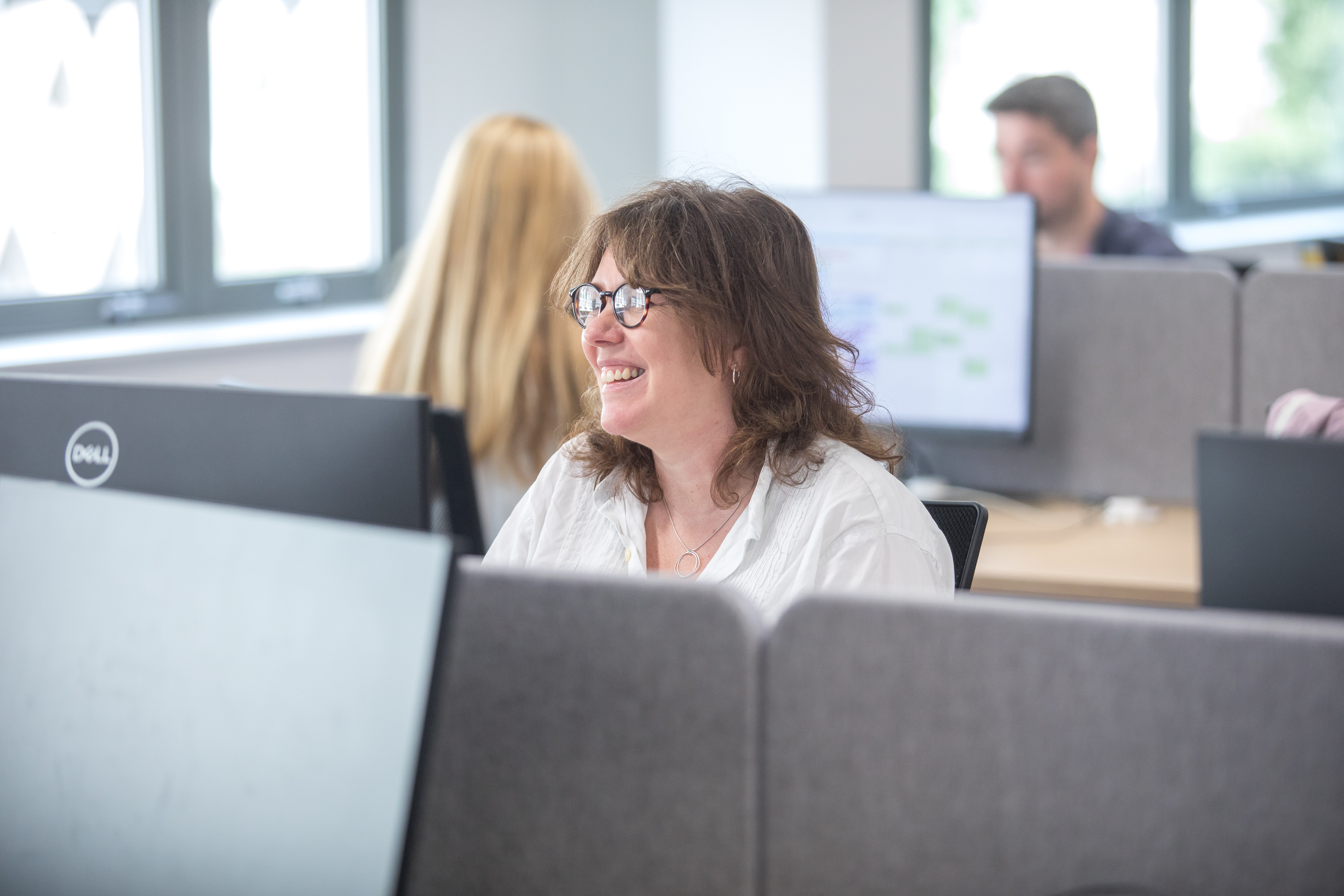 Photograph of female office employee smiling at desk