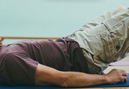 Man lying on floor doing back exercises